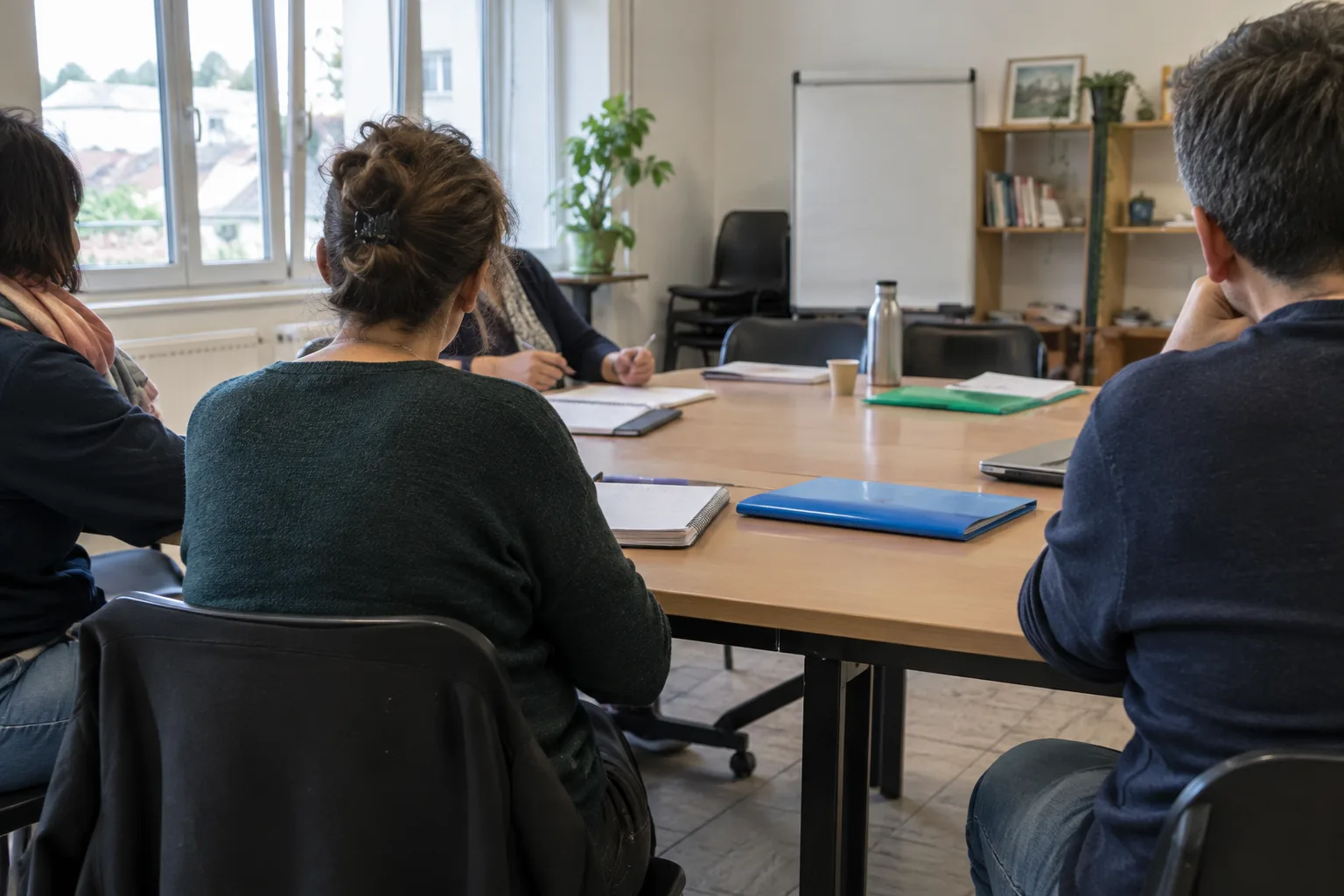 Salle associative préparée pour une rencontre autour de l’entrepreneuriat, avec des dossiers et des chaises autour d’une table.
