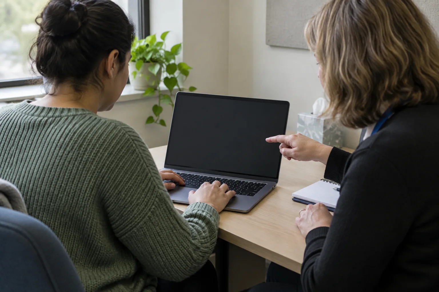 Une personne utilise son ordinateur tandis qu’une conseillère l’accompagne sans prendre sa place.